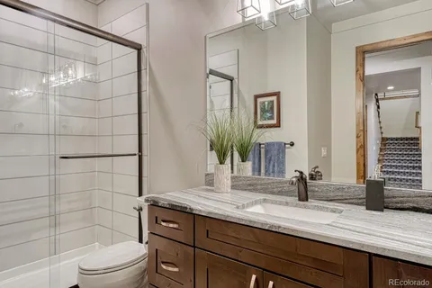 a bathroom with a granite countertop sink toilet a mirror a vanity and shower