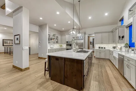 a large kitchen with granite countertop a large counter top a sink stainless steel appliances and cabinets