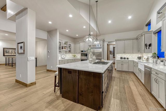 a large kitchen with granite countertop a large counter top a sink stainless steel appliances and cabinets