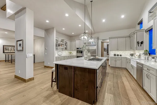 a large kitchen with granite countertop a large counter top a sink stainless steel appliances and cabinets