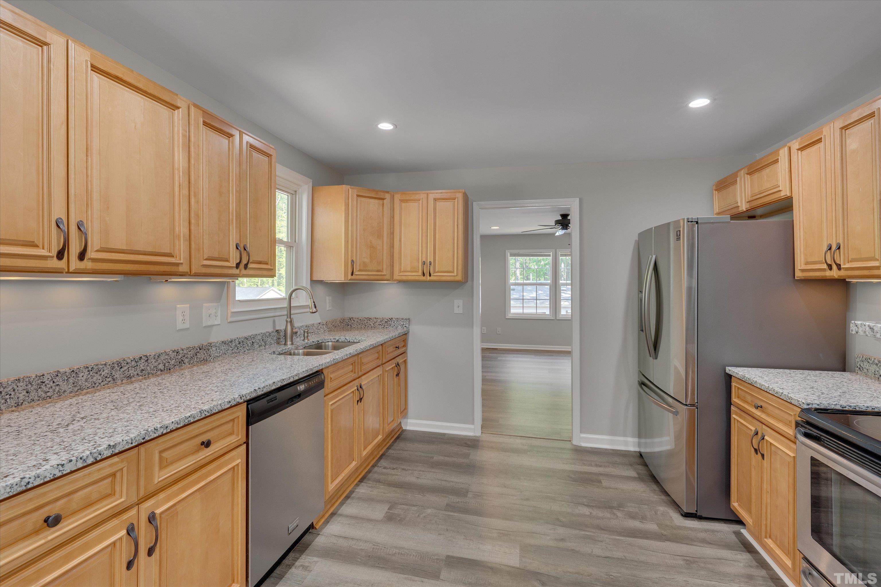 308 South Mineral Springs Road Durham, NC 27703 - Photo 14 of 42 a kitchen with stainless steel appliances granite countertop a refrigerator a sink dishwasher and wooden cabinets with wooden floor