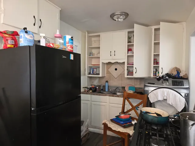 a kitchen with a refrigerator a sink dishwasher a dining table and chairs with wooden floor