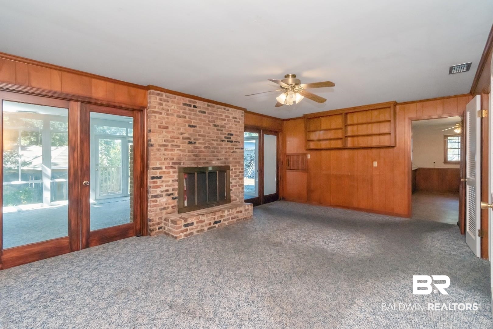 4543 Kingsway Drive Mobile, AL 36608 - Photo 7 of 28 Family room with a brick fireplace, visible vents, ornamental molding, wood walls, and dark carpet