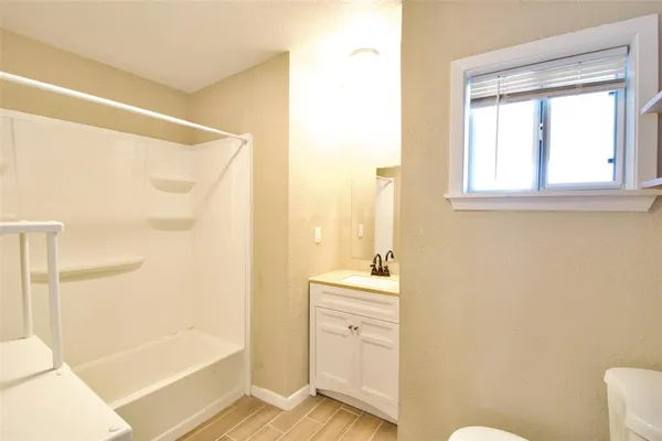 a bathroom with a sink a toilet a window and a glass door shower