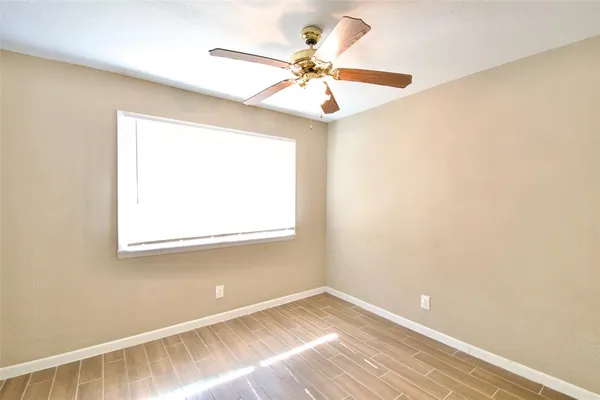 an empty room with a window and a fan