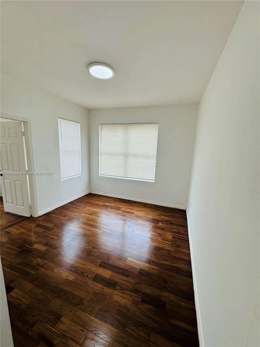 144 Northeast 43rd Street, Unit 2 Miami, FL 33137 - Photo 6 of 10 an empty room with wooden floor and windows