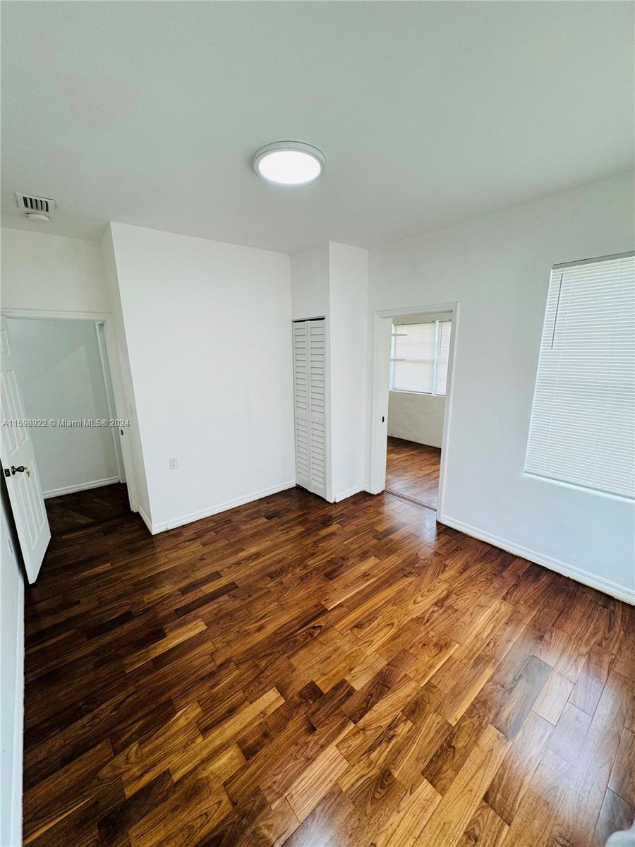 144 Northeast 43rd Street, Unit 2 Miami, FL 33137 - Photo 7 of 10 a view of empty room with wooden floor and cabinet