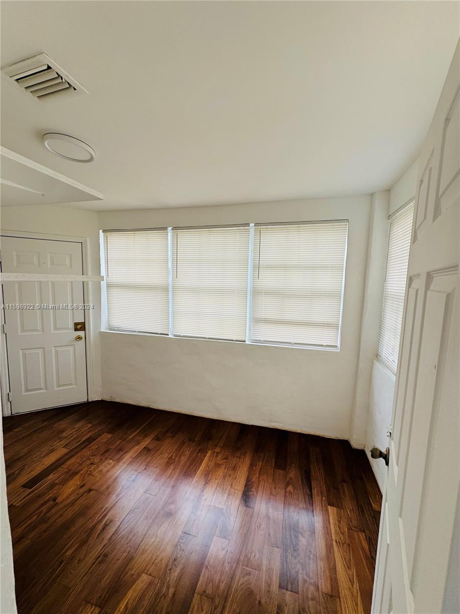 144 Northeast 43rd Street, Unit 2 Miami, FL 33137 - Photo 8 of 10 an empty room with wooden floor and windows
