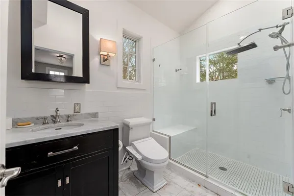 a bathroom with a toilet a sink a mirror and a shower