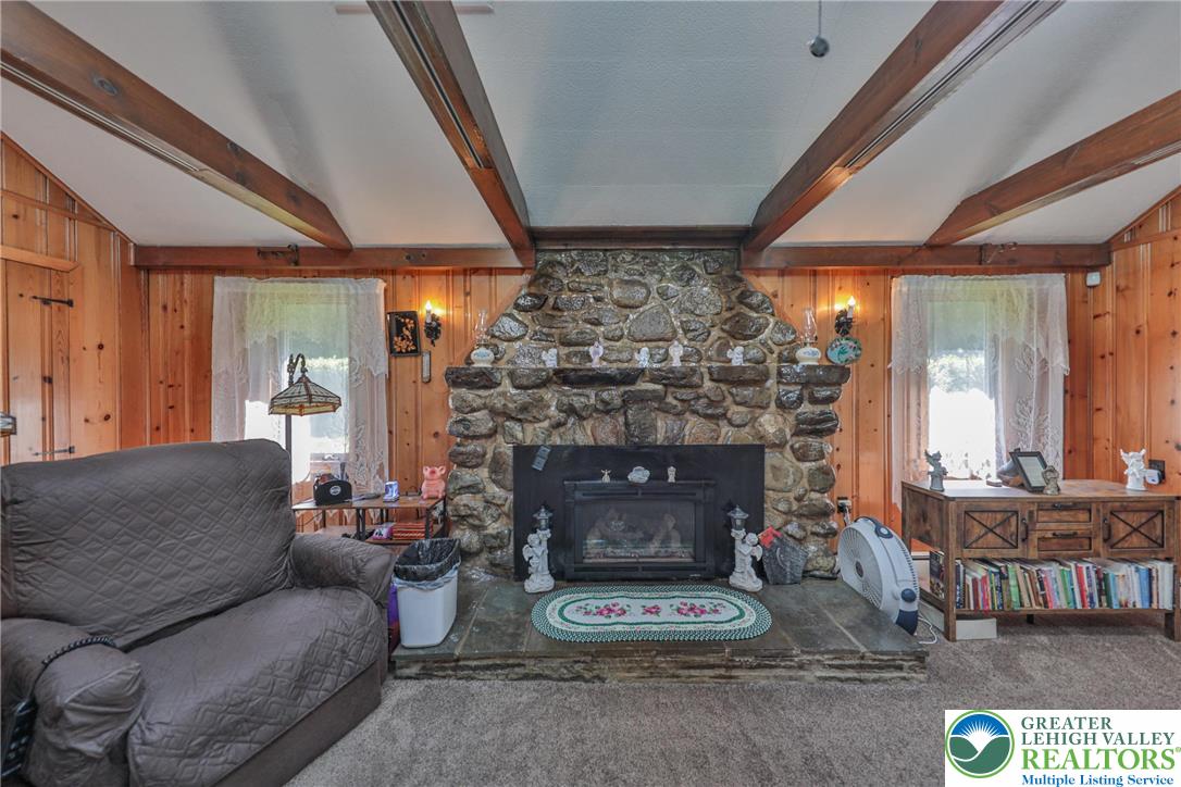 331 Cranberry Creek Road Cresco, PA 18326 - Photo 17 of 95 A striking stone fireplace creates a focal point, flanked by warm wood paneling and exposed ceiling beams in this cozy living space.