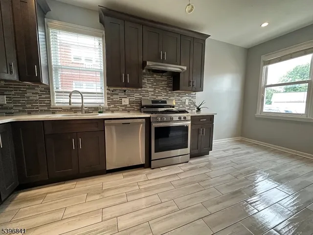a kitchen with stainless steel appliances granite countertop a stove a sink and a microwave
