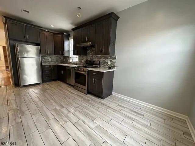 a kitchen with stainless steel appliances granite countertop a refrigerator and a stove top oven