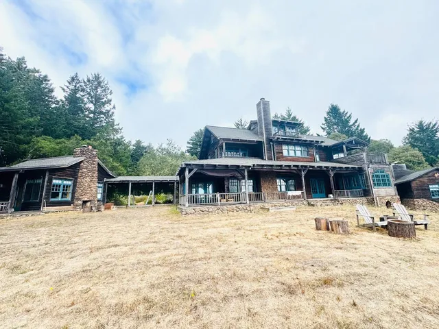 a front view of a house with a big yard and large trees