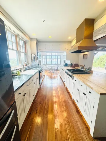 a large kitchen with stainless steel appliances granite countertop a lot of counter space and wooden floors