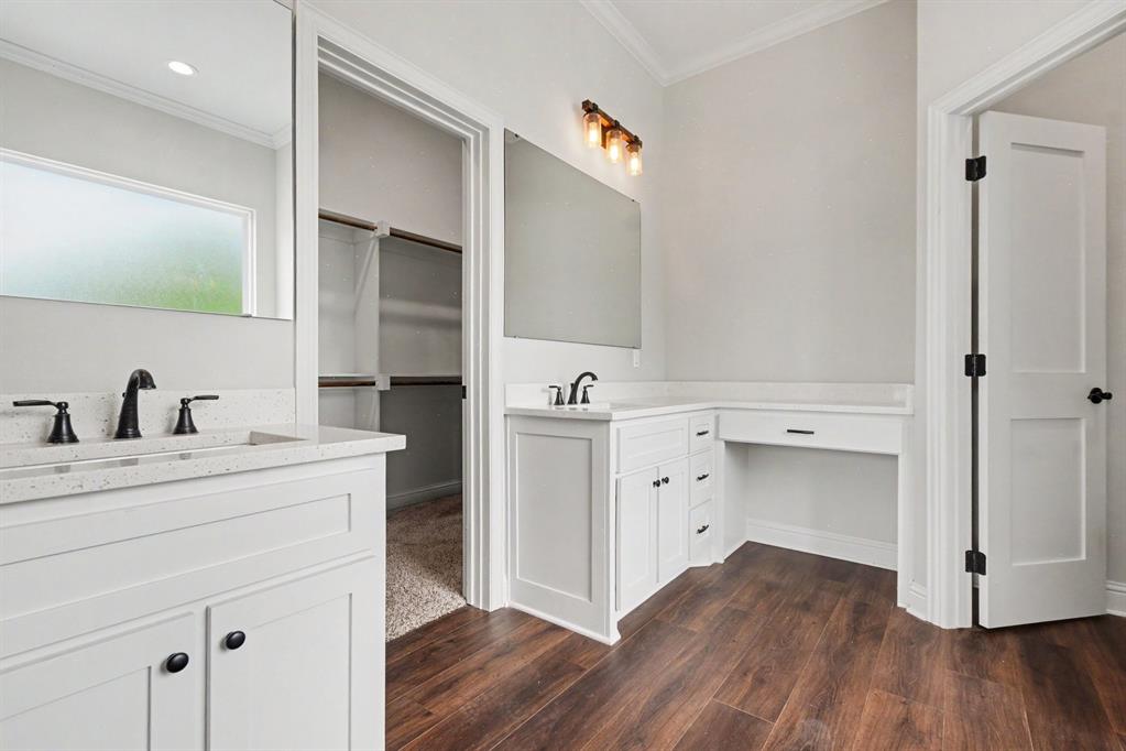 530 P R 491 Leonard, TX 75452 - Photo 18 of 35 Bathroom featuring wood-finish flooring, white cabinetry with dark hardware, a vanity with a light-colored countertop and dark-finish fixtures, and a separate built-in desk area