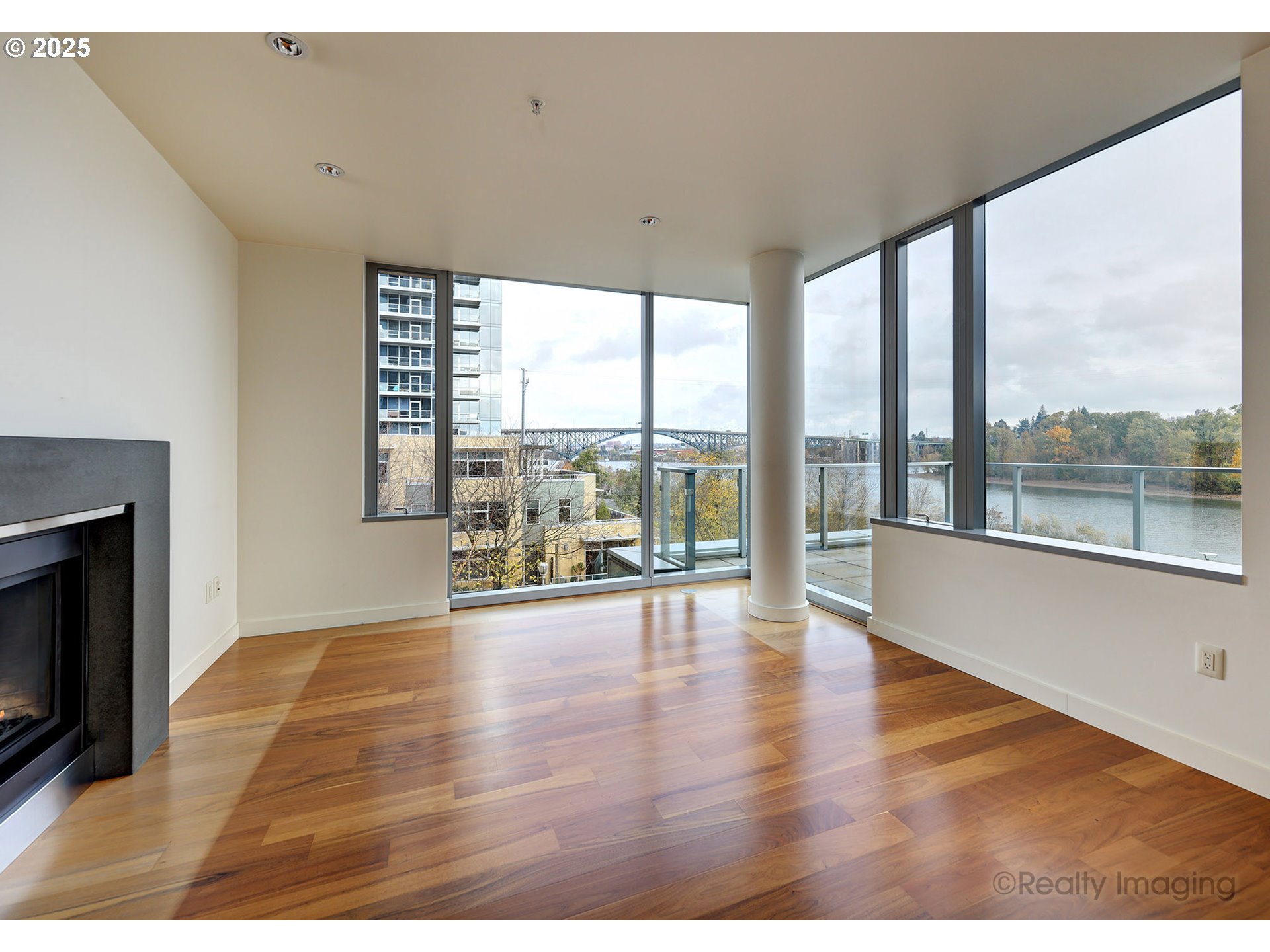 841 Southwest Gaines Street, Unit 319 Portland, OR 97239 - Photo 9 of 44 a view of an empty room with wooden floor and a fireplace