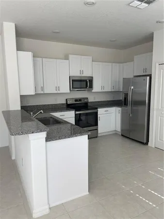 a kitchen with stainless steel appliances granite countertop a stove top oven a refrigerator a sink and dishwasher