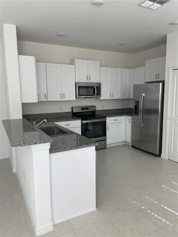 a kitchen with stainless steel appliances granite countertop a stove top oven a refrigerator a sink and dishwasher