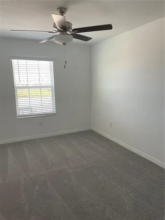 an empty room with a window and a fan