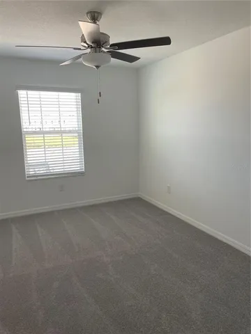 an empty room with a window and a fan