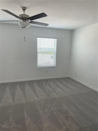 an empty room with a window and a fan