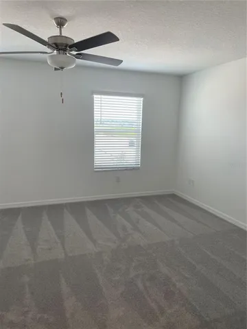 an empty room with a window and a fan
