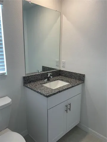 a bathroom with a granite countertop sink and a toilet