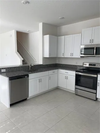 a kitchen with granite countertop white cabinets and stainless steel appliances