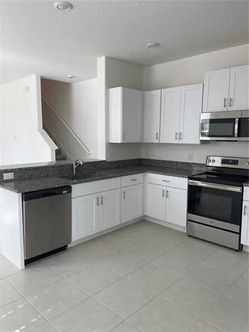 a kitchen with granite countertop white cabinets and stainless steel appliances