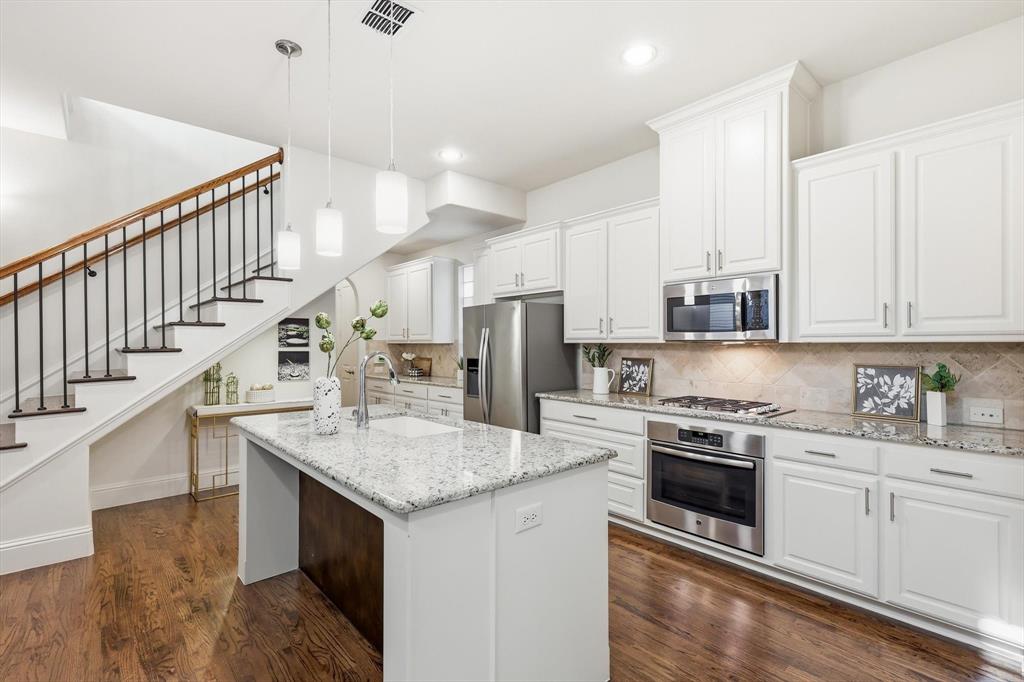 516 Sandy Lane Flower Mound, TX 75022 - Photo 11 of 38 Open-concept kitchen featuring white cabinetry, granite countertops, and stainless steel appliances, including an oven and microwave
