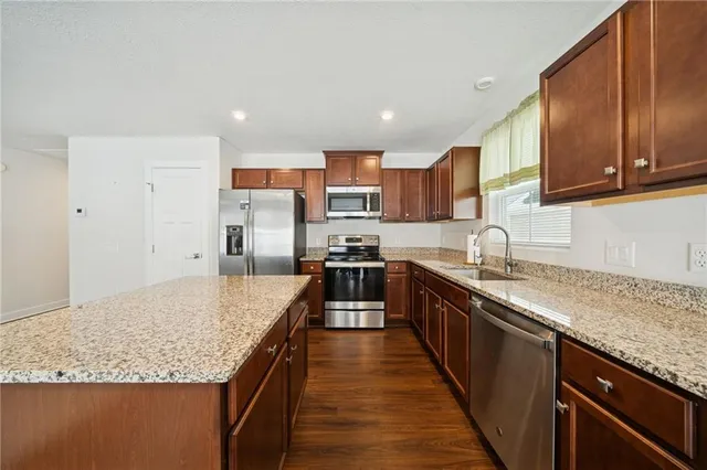 a large kitchen with granite countertop lots of counter space sink and stainless steel appliances