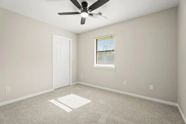 an empty room with windows and fan