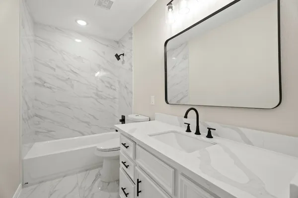 a bathroom with a double vanity sink toilet mirror and bathtub