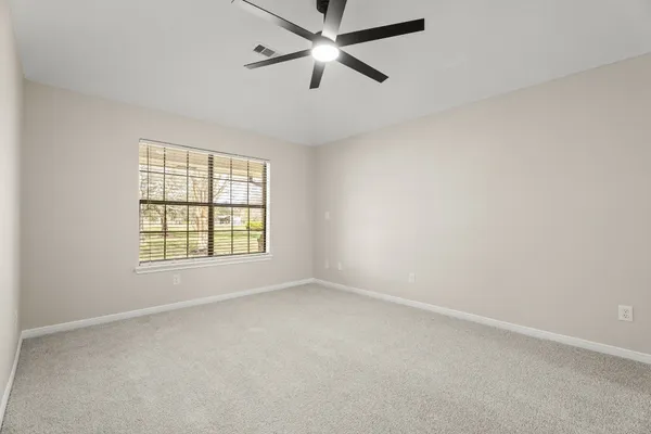 an empty room with a window and a fan