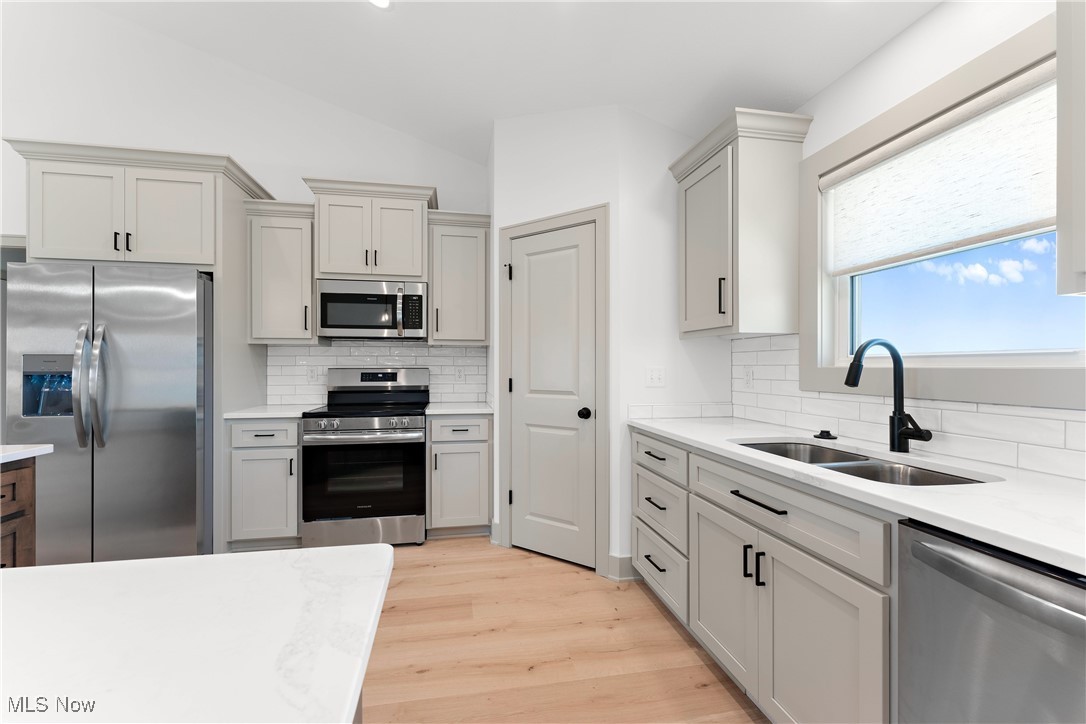 8664 Akron Road Marshallville, OH 44645 - Photo 5 of 29 Kitchen featuring light hardwood / wood-style floors, sink, tasteful backsplash, gray cabinetry, and appliances with stainless steel finishes