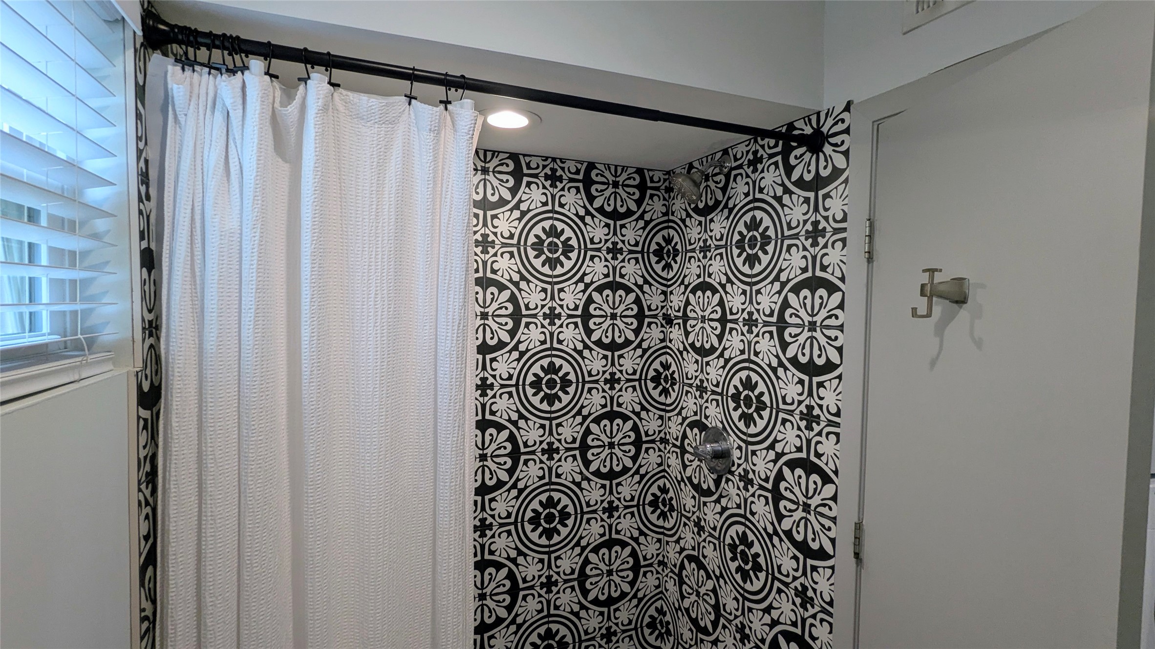 4505 Teri Road, Unit A Austin, TX 78744 - Photo 19 of 23 A stylish shower features striking black and white patterned tile and a window with privacy blinds.