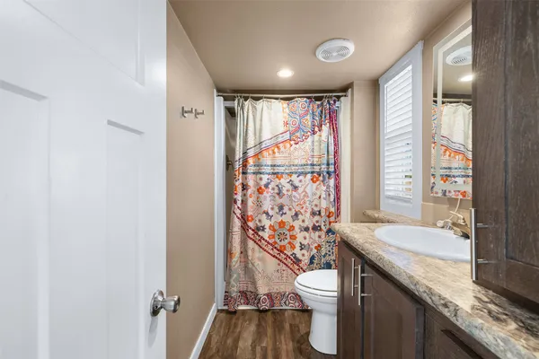a bathroom with a granite countertop sink a toilet and shower curtain