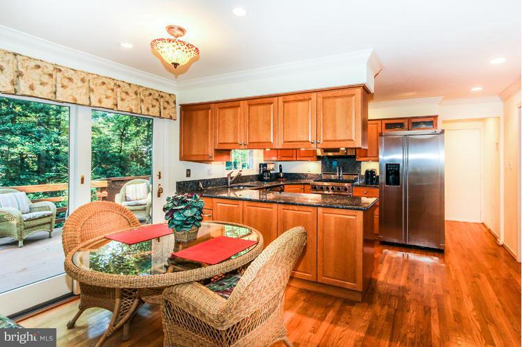 2600 Penny Royal Lane Reston, VA 20191 - Photo 14 of 30 a kitchen with stainless steel appliances granite countertop a stove a refrigerator a kitchen island with chairs a refrigerator and wooden floor