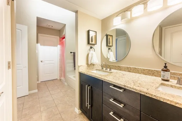 a bathroom with a granite countertop double vanity sink and a mirror