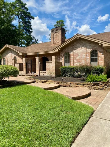a front view of a house with garden and trees