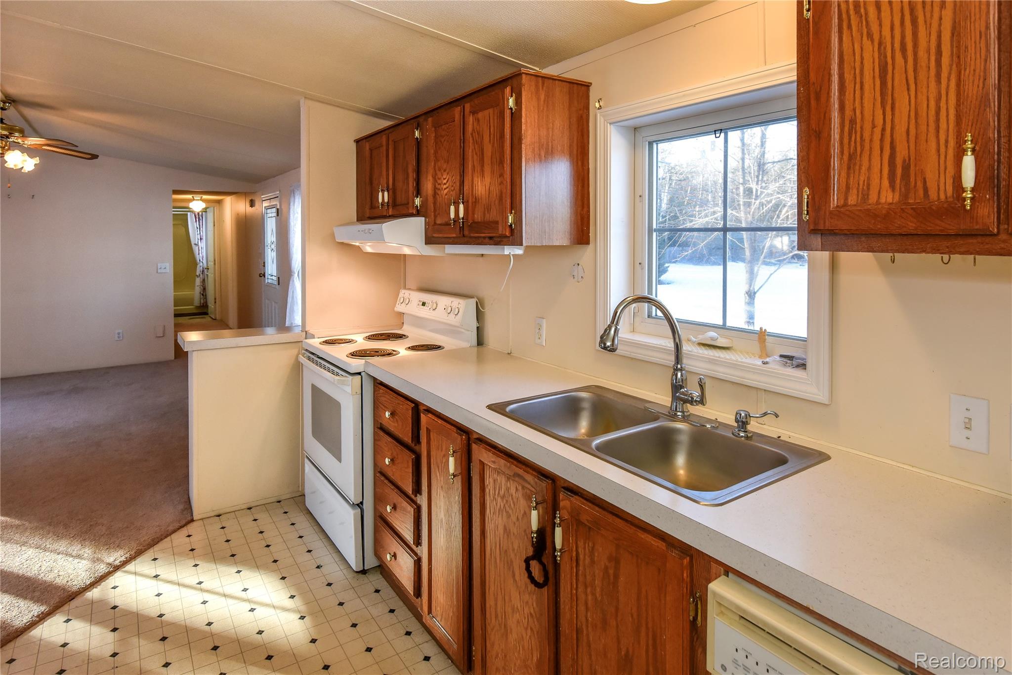 1094 Blamer Road Fairview, MI 48621 - Photo 32 of 97 Kitchen with white appliances, light carpet, light countertops, wood finish cabinetry, and lofted ceiling