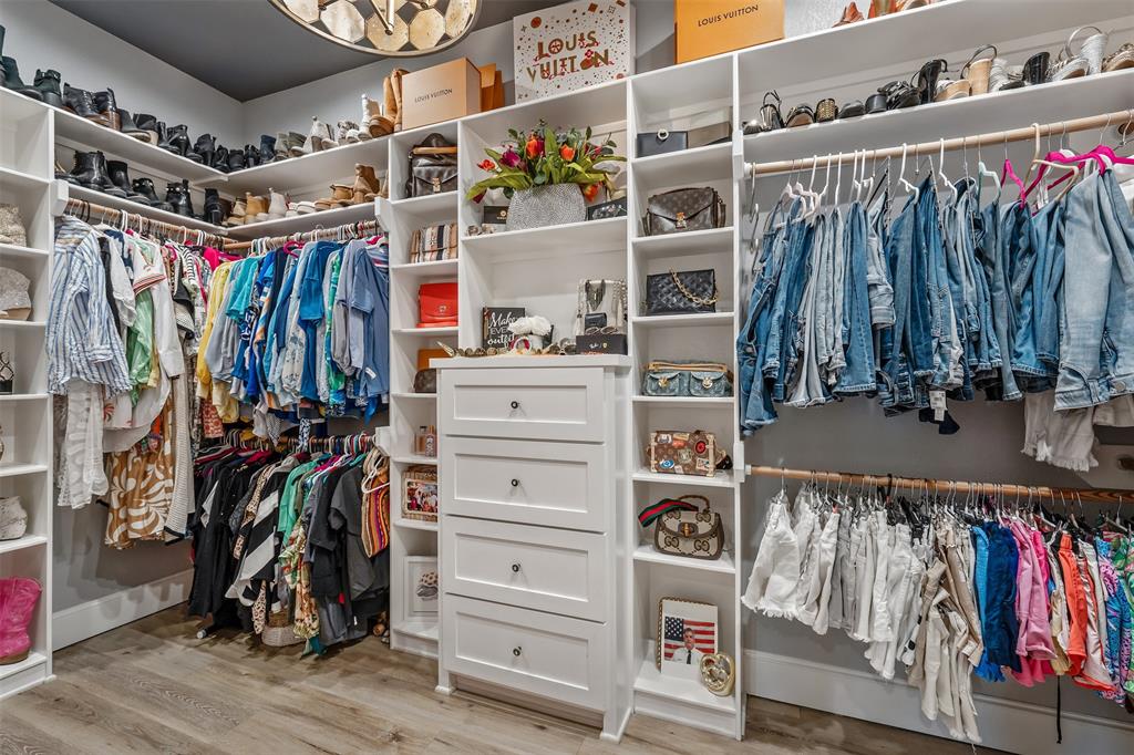 16241 Big Oak Bay Road Tyler, TX 75707 - Photo 21 of 40 Custom closet system featuring extensive shelving, multiple hanging rods, built-in drawers with dark hardware, and wood-finish flooring