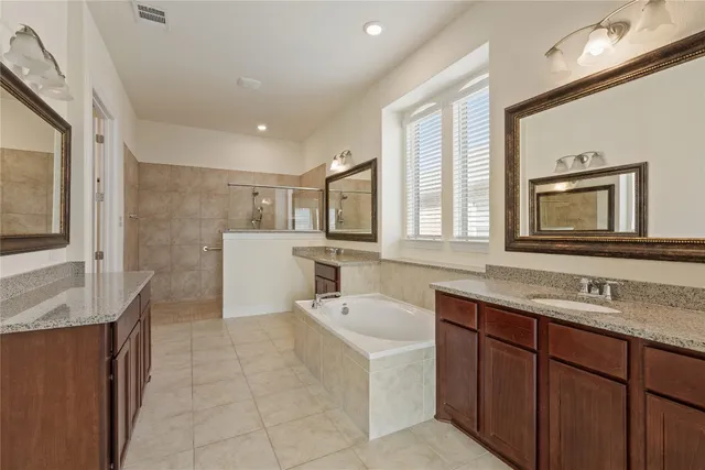 a bathroom with a sink double vanity granite tub shower and mirror
