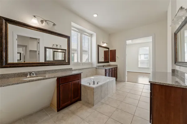 a bathroom with a sink double vanity granite tub shower and mirror