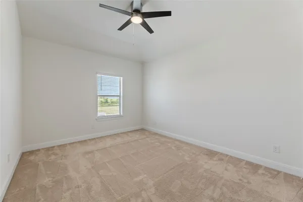 an empty room with a ceiling fan and bathroom view