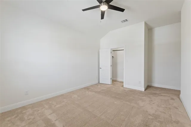 an empty room with a ceiling fan and carpet