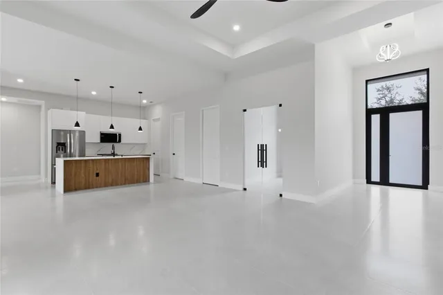 a view of an empty room with kitchen and a window