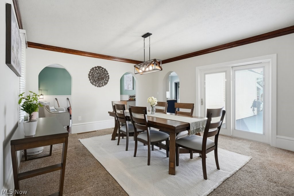 23055 Snell Road Columbia Station, OH 44028 - Photo 18 of 50 Dining area featuring a contemporary chandelier, sliding glass doors, arched doorways, crown molding, and neutral-toned carpet