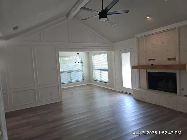 an empty room with wooden floor a fireplace and windows
