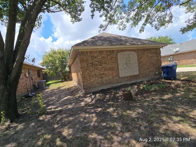 a view of a stone house with a large tree